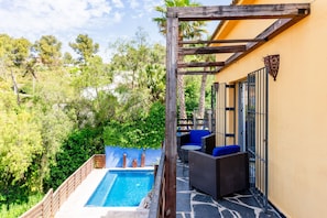 A poolside area with a wooden pergola, outdoor seating, and a view of a natural landscape. - Villa Charma - Three Bedroom Villa, Sleeps 9 (Vora-sitges)