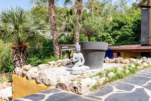 A stone statue in a garden with palm trees and a stone pathway. - Villa Charma - Three Bedroom Villa, Sleeps 9 (Vora-sitges)