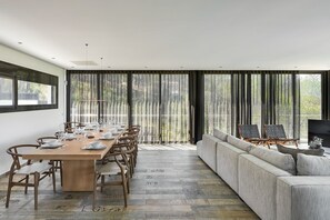 Ein moderner Essraum mit einem langen Tisch, gedeckt für sechs Personen, einer Couch und einem Fernseher.