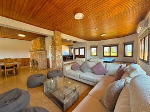 A spacious living area with a stone fireplace, a sofa set, and a glass coffee table. - Serenity Villa - Private Heated Swimming Pool (Liopetri)
