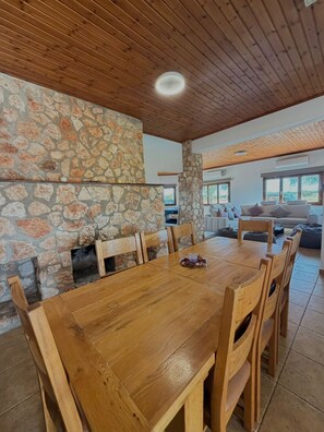 A wooden dining table with chairs, a stone wall, and a view of the outdoors. - Serenity Villa - Private Heated Swimming Pool (Liopetri)