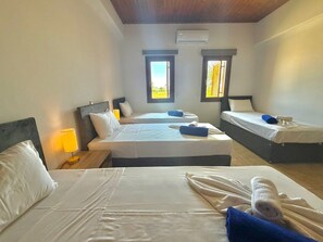 A hotel room with two beds, a nightstand with a lamp, and two windows. - Serenity Villa - Private Heated Swimming Pool (Liopetri)