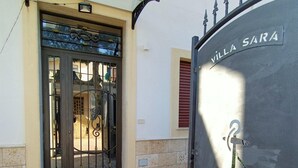 A building entrance with a metal gate labeled 'VILLA SARA,' a tiled entrance area, and a compass-like design on the ground. - B&B Villa Sara Falconara (Butera)