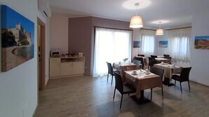 A dining area with tables, chairs, and a kitchen in the background. - B&B Villa Sara Falconara (Butera)