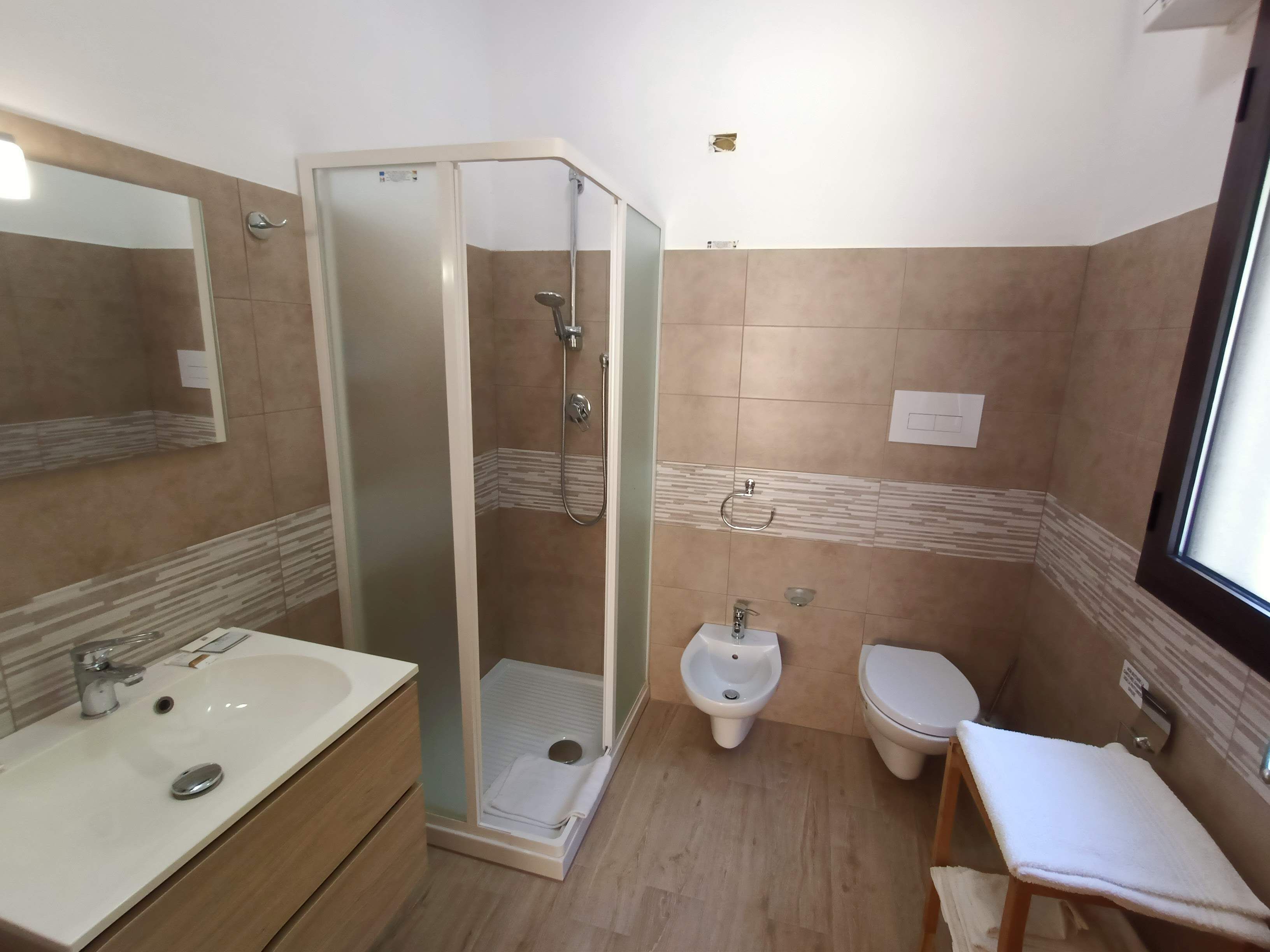 A bathroom with a shower, bidet, toilet, and a sink.