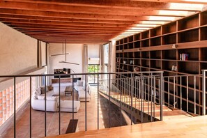 Un interior moderno con una escalera, un conjunto de sofás y una estantería.