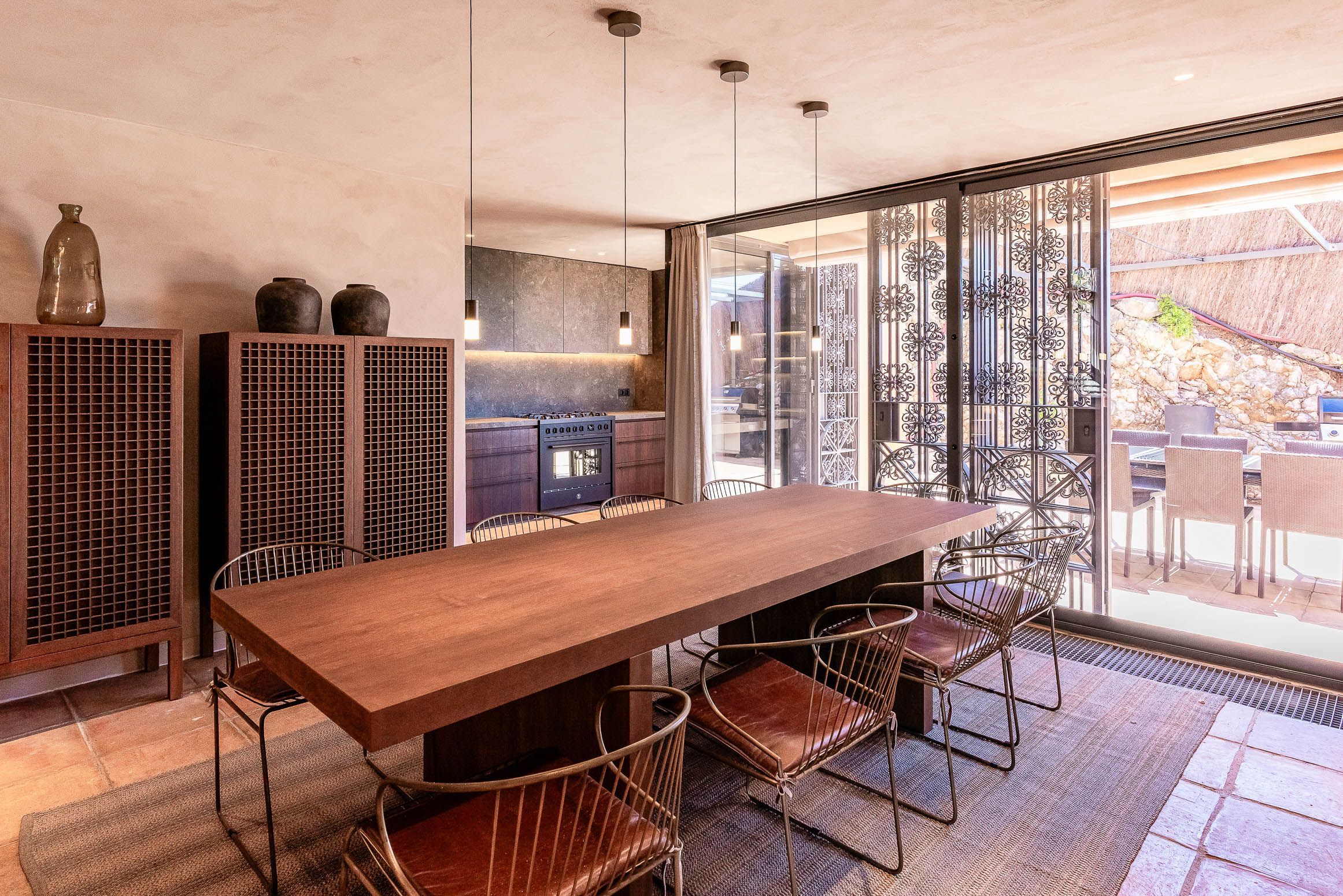 Eine moderne Küche mit einem Holztisch und Metallstühlen, einem eingebauten Herd und einem großen Fenster mit Blick.