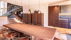 Eine moderne Küche mit Einbauofen und Essbereich mit langem Holztisch und Metallstühlen.