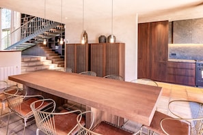 Una cocina moderna con horno empotrado y comedor con una mesa de madera grande y sillas de metal.