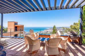 Une terrasse avec des chaises en osier et vue sur la mer.