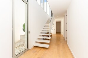 Ein modernes Interieur mit einer Holztreppe, einer Glastür und einer Pflanze.