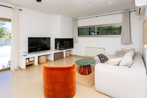 Ein modernes Wohnzimmer mit Flachbildfernseher, einer Couch, einem Couchtisch und einem Kamin.