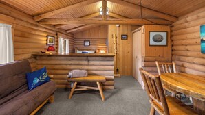 A log cabin interior with a wooden bench, a wooden table, and a sofa with a cushion. - New! Birdsong Log Cabin, Mountain views, firepit (Bigfork)