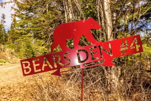 A red sign with a bear silhouette and the text 'BEARSDEN #4' in a forested area. - New! Bears Den Log Cabin, Mountain views, firepit (Bigfork)