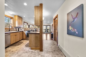 A modern kitchen with wooden cabinets, a central island, and a large window. - 3 Bedroom Cabin, Mountain & Lake Views, Glacier (Bigfork)