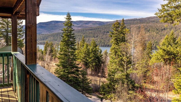 Puinen terassi, jolta avautuu näkymä metsäiselle alueelle, ja kauempana siintää järvi sekä vuoristo.