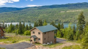 Kaksikerroksinen rakennus, jonka katto on viherkatto, ja jonka ympärillä on metsäinen alue sekä järvi.