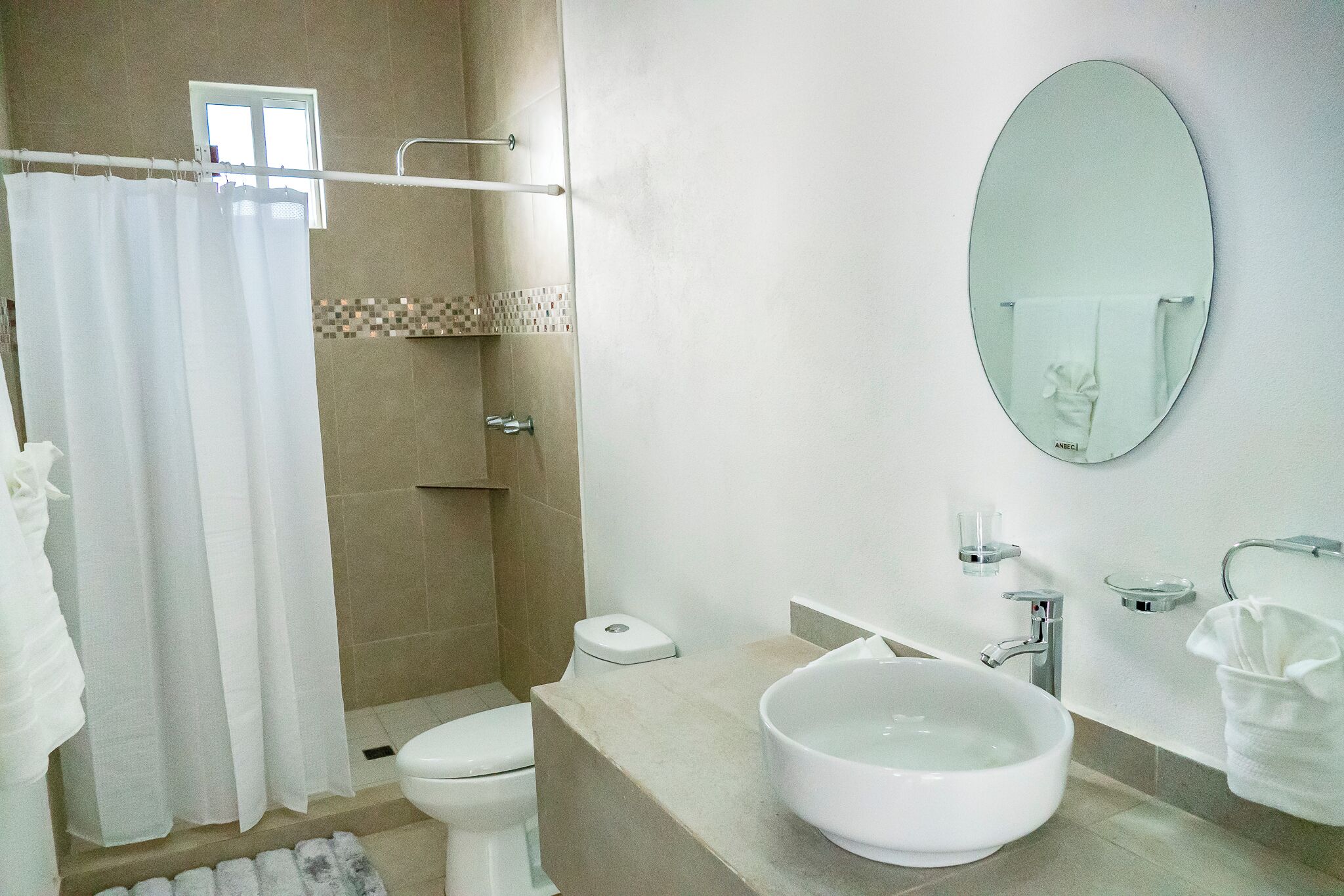 Une salle de bain équipée d’une douche, de toilettes, d’un lavabo et d’un miroir.