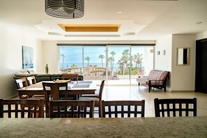 A spacious living area with a dining table, chairs, a sofa, and a view of the ocean through large windows. - Casa Postal (Puerto Peñasco)