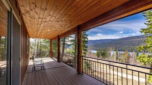 Un terrazzino in legno con vista su un lago e una foresta.