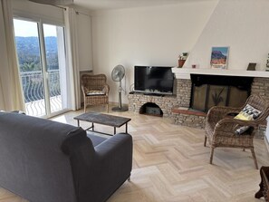 Un salon comprenant un canapé, un téléviseur, une cheminée et un balcon avec vue.