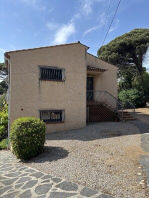 A two-story building with a stone-paved entrance, a small staircase, and a metal railing. - Gîte 500m from the sea in Les Issambres - first floor (ROQUEBRUNE SUR ARGENS)