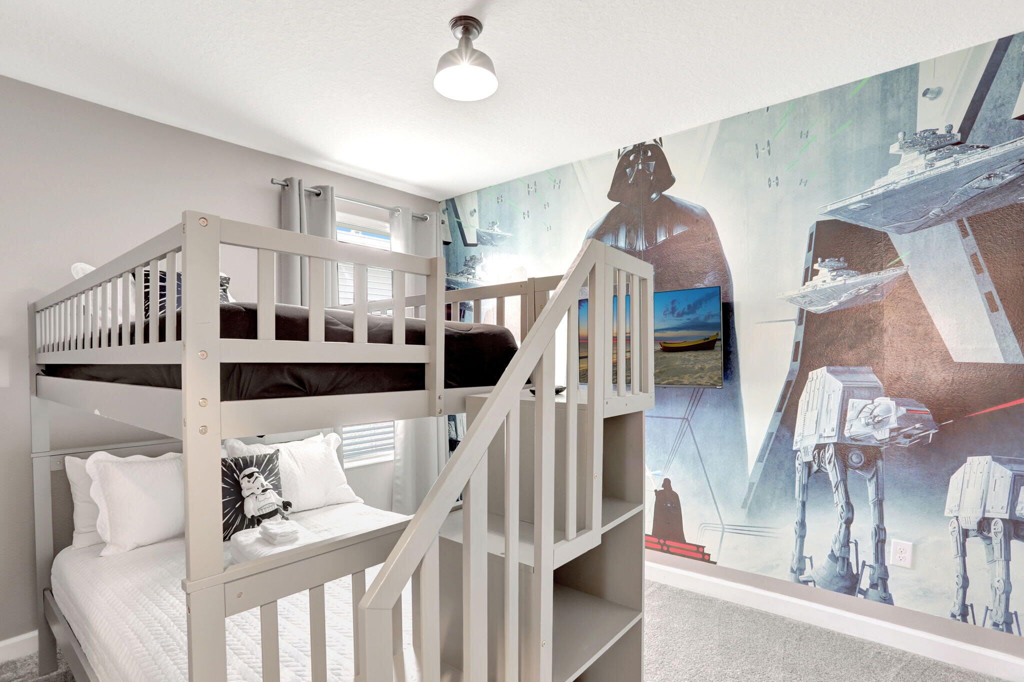 Habitación con literas, un mural de Star Wars, una ventana y una lámpara en el techo.