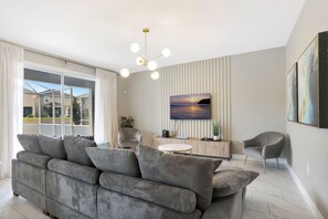 Ein modernes Wohnzimmer mit einem grauen Sofa, einem runden Couchtisch und einem Gemälde vom Sonnenuntergang.