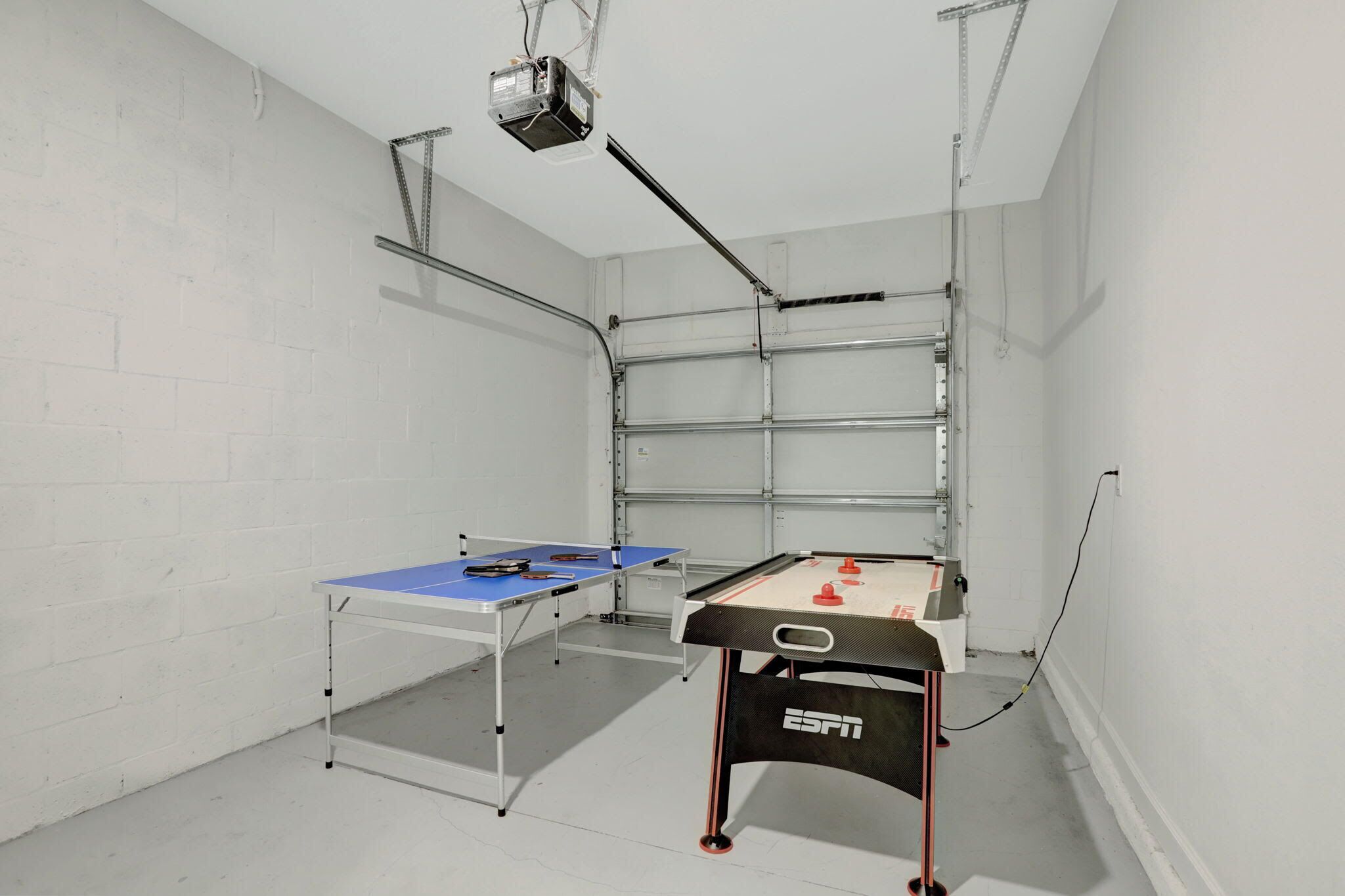 A room with two foosball tables, a projector, and a metal shelving unit.
