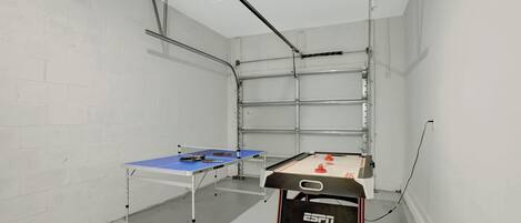 A room with two foosball tables, a projector, and a metal shelving unit.