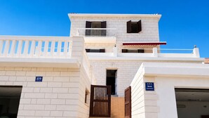 Un immeuble à plusieurs étages, doté d’une façade blanche, d’un balcon au deuxième étage et d’un escalier menant à l’entrée.