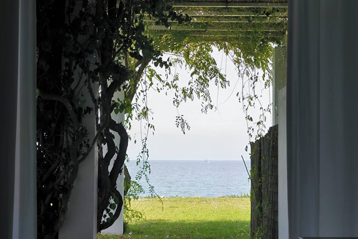Un umbral abierto que da a un balcón con vista al mar.