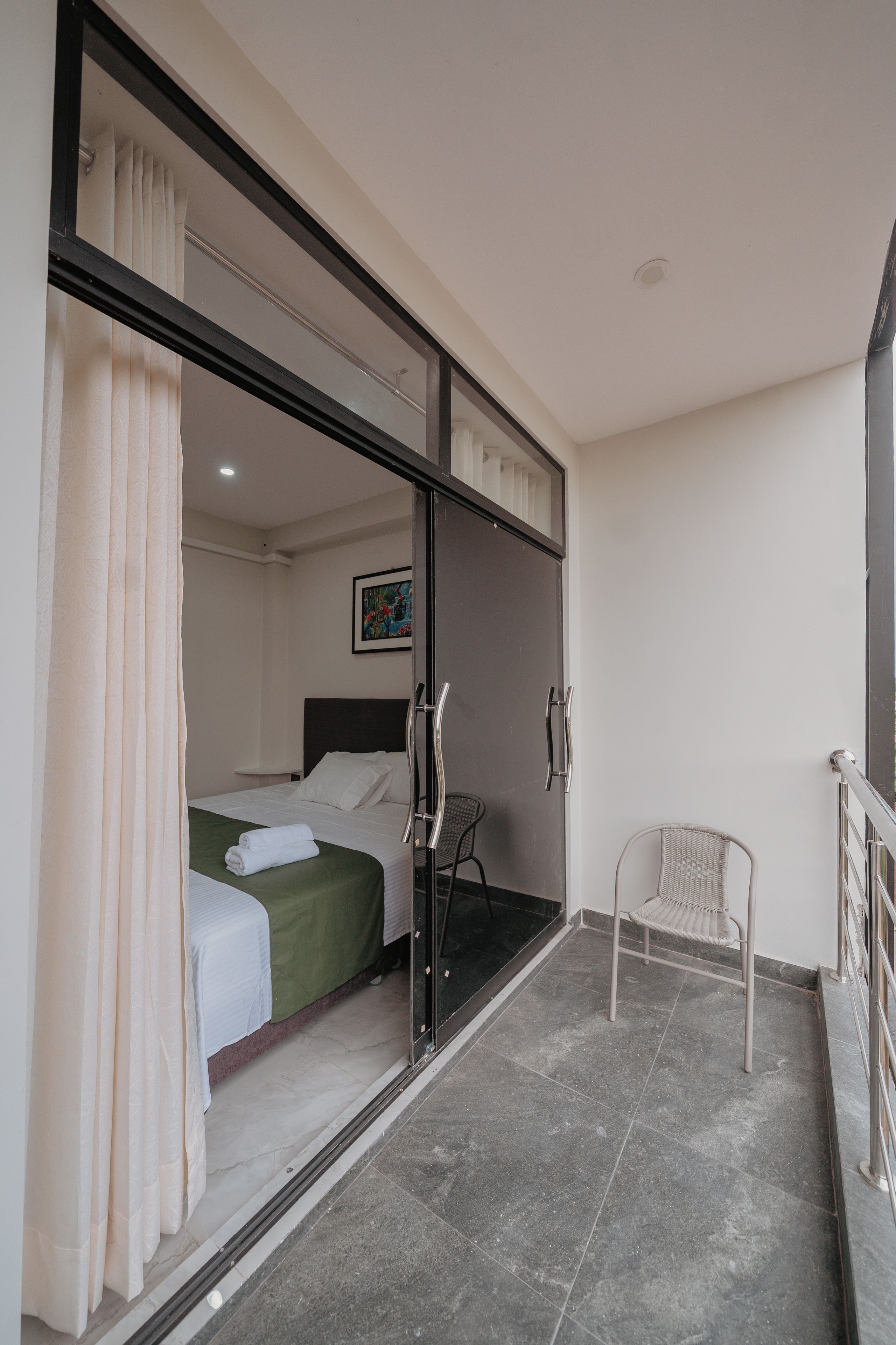 A hotel room with a bed, a chair, and a balcony.