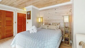 A bedroom with a bed, wooden ceiling, a wall-mounted shelf, and a door. - 2 Story Townhome-Walk to Downtown Lewes! (Lewes)
