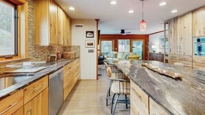 A modern kitchen with wooden cabinets, a marble countertop, and a bar area. - 2 Story Townhome-Walk to Downtown Lewes! (Lewes)