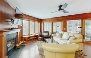 A living room with a fireplace, a sofa, a television, and a ceiling fan.