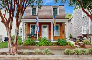 A two-story house with a front porch, a mailbox, and two flags.