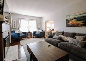 Ein Wohnzimmer mit Kamin, zwei Sofas, einem Couchtisch und einem Gemälde an der Wand.