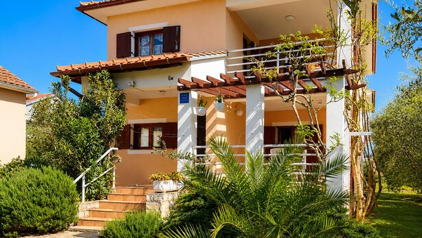 A two-story house with a balcony, steps leading to the entrance, and surrounding greenery. - Lovely apartment in Kukljica with WiFi (Kukljica)