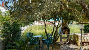 An outdoor seating area with chairs and a table, surrounded by greenery and a stone pathway. - Lovely apartment in Kukljica with WiFi (Kukljica)