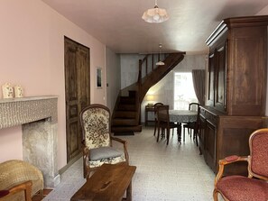 Ein Wohnzimmer mit Kamin, einer Holztreppe, einem Essbereich und einem großen Holzschrank.