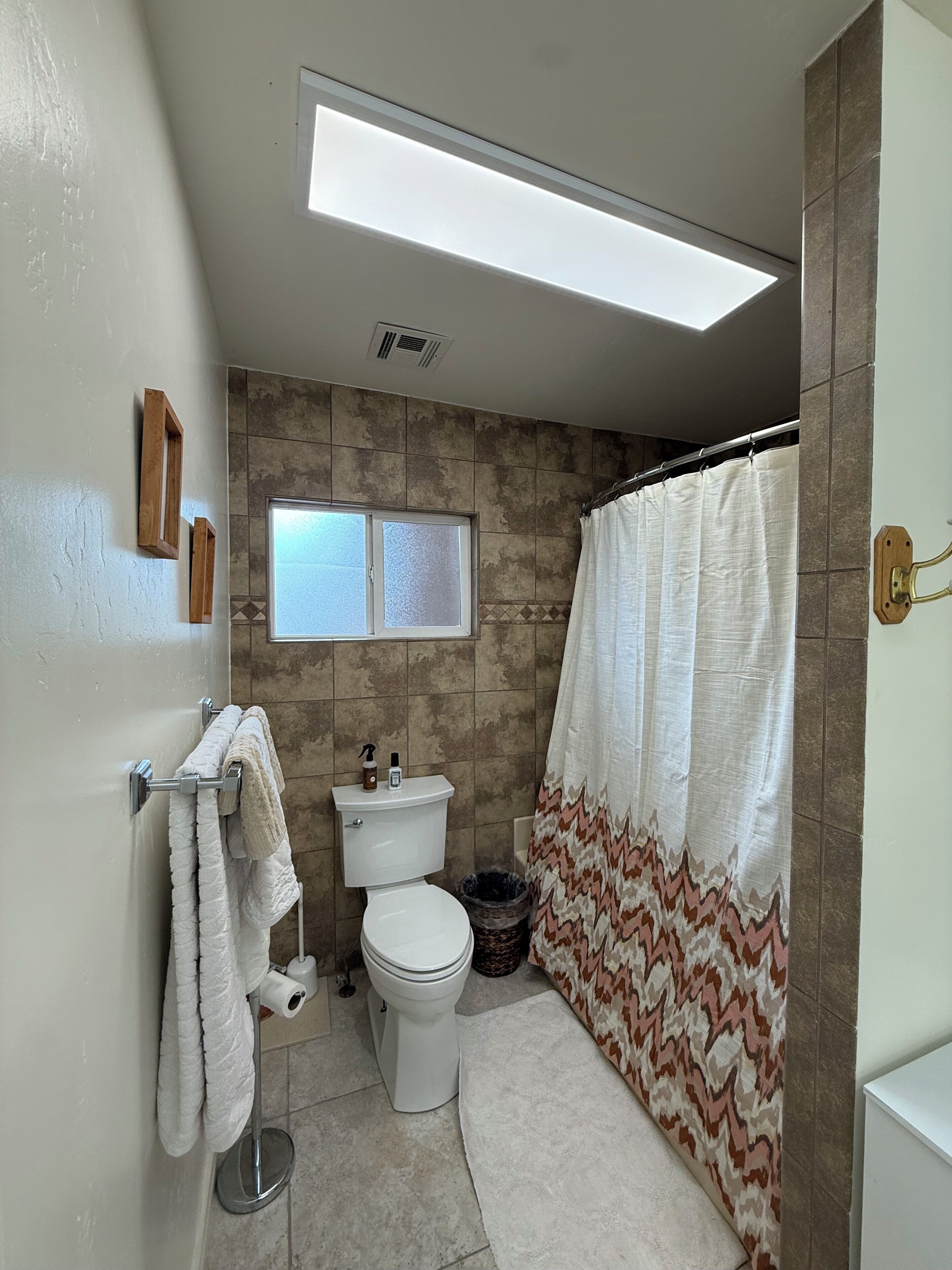 A bathroom with a toilet, sink, shower curtain, and towel rack.