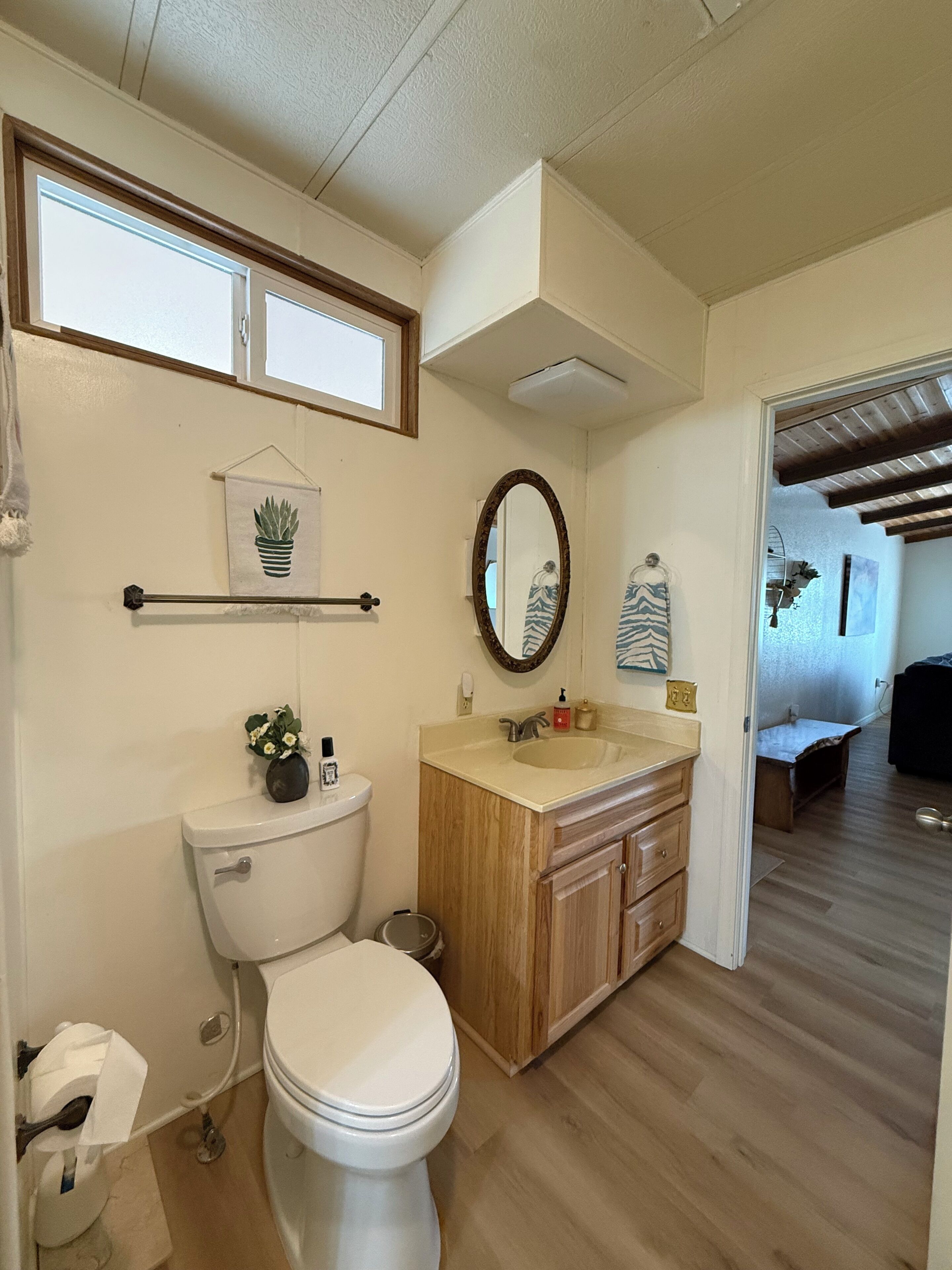 Ein Badezimmer mit Toilette, Waschbecken, Spiegel und Holzschränken.