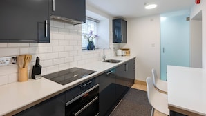 Een moderne keuken met zwarte kastjes, een wit aanrechtblad en een ingebouwde oven.