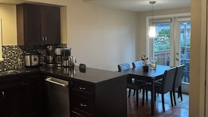 A modern kitchen with a central island, dark cabinetry, and a dining area with a table and chairs. - Vancouver View Home w/ Hot Tub Near Downtown (Vancouver)