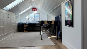 A modern attic bedroom with a skylight, a bed, a desk, and a poster on the wall. - Vancouver View Home w/ Hot Tub Near Downtown (Vancouver)