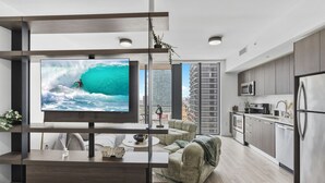 Ein modernes Wohnzimmer mit Fernseher, Sofa und Küchenzeile.