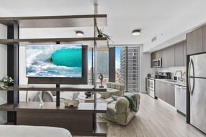 A modern living room with a TV, sofa, and kitchen area. - Luxury High-Rise Bay Views + Pool + Parking Steps to Bayside & Brickell (Miami)