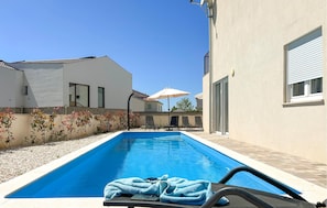 A swimming pool with lounge chairs and umbrellas, surrounded by buildings. - Gorgeous home in Stancija Vergotini (Stancija Vergotini)