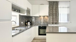 Een moderne keuken met witte kasten, een inbouwoven, een koffiezetapparaat en een magnetron.